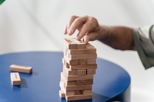 Close-up of a man's hand playing a game of Jenga, focusing on skill and precision.