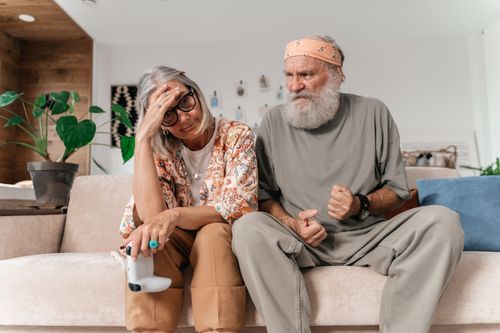 Free Senior couple expressing frustration while sitting on sofa indoors. Stock Photo