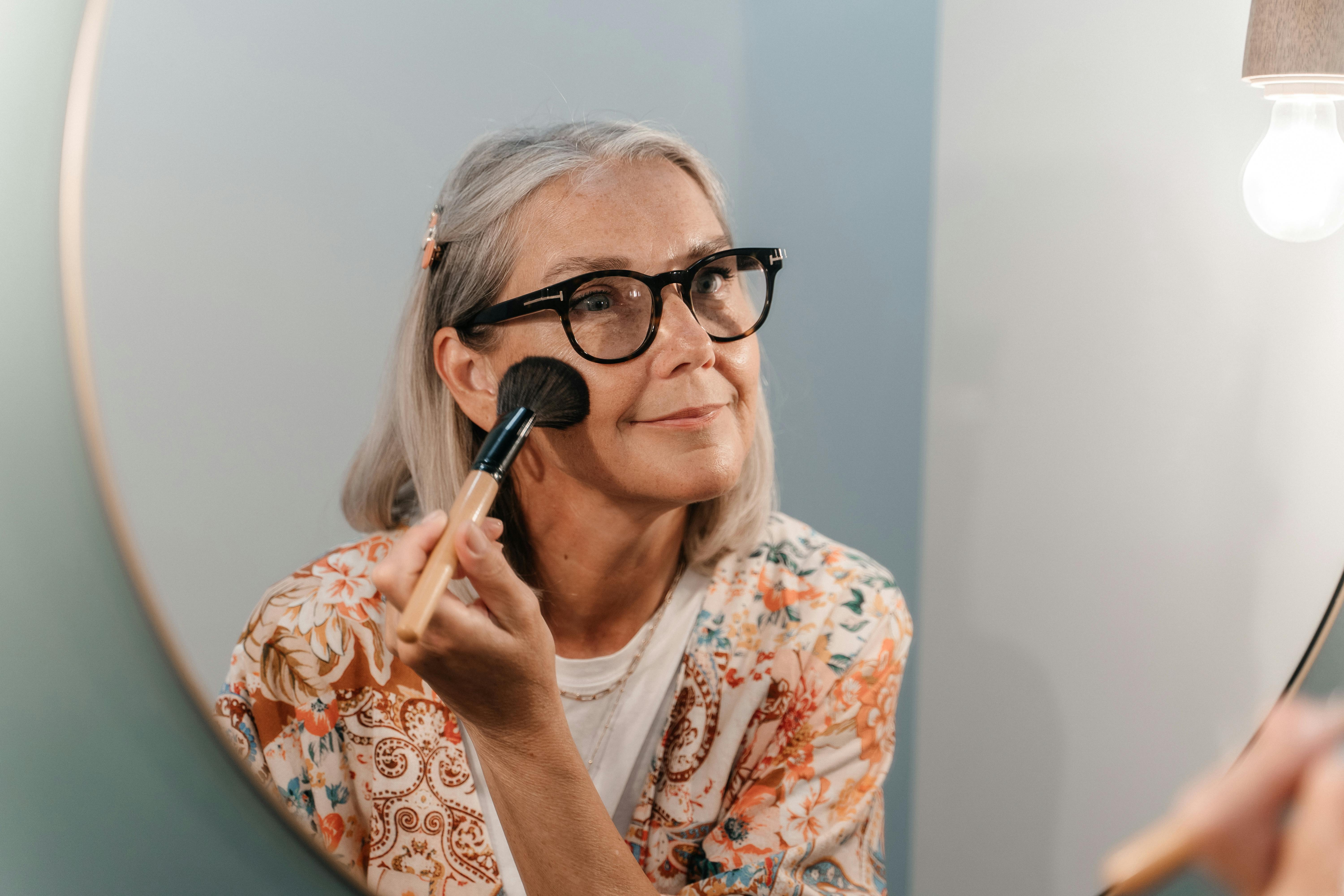 elderly woman doing her makeup in mirror