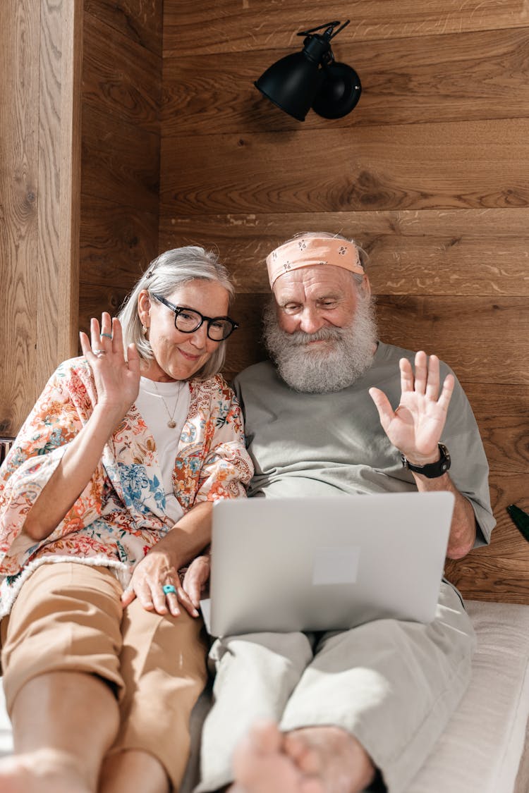 Senior Couple Connecting With Family Through Internet, Wooden Wall In Background