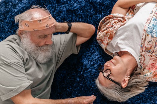 A senior couple lying together on a plush blue carpet, sharing a serene moment.