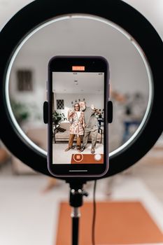 An elderly couple poses joyfully captured through a smartphone screen using a ring light. Perfect for modern lifestyle themes.