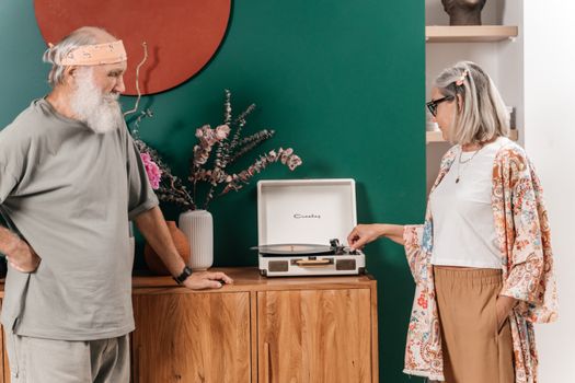 Senior Couple Playing Vinyl Record in an Interior with a Dark Green Wall