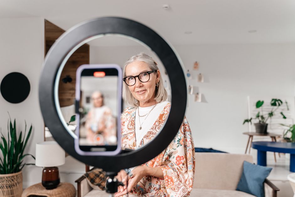 How Micro Influencers Use Media Kit Templates to Land Brand Deals Elegant senior woman recording a video using a smartphone and ring light in a stylish home setting.