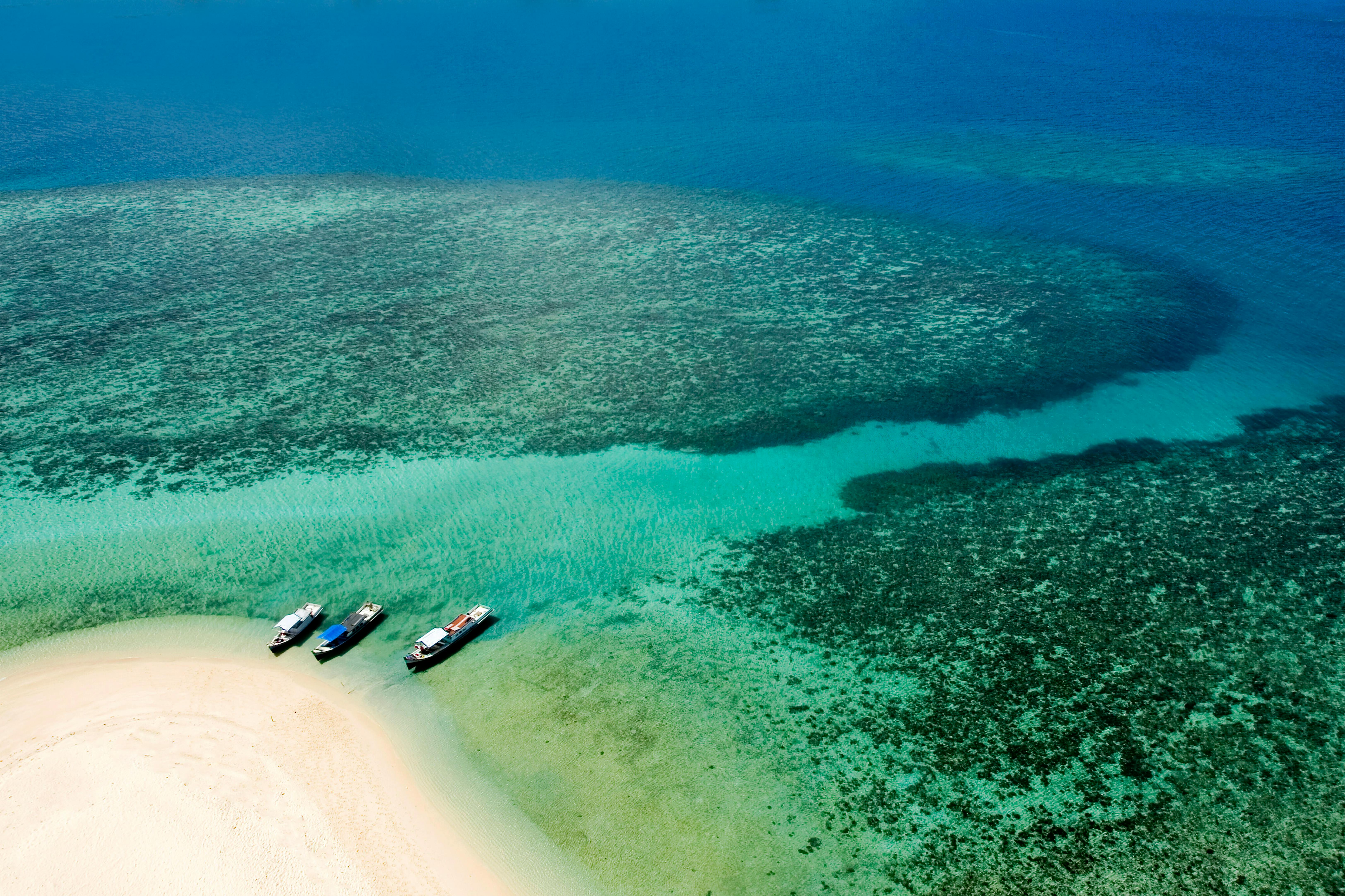 Stunning aerial view of boats moored near a sandy beach with turquoise water.