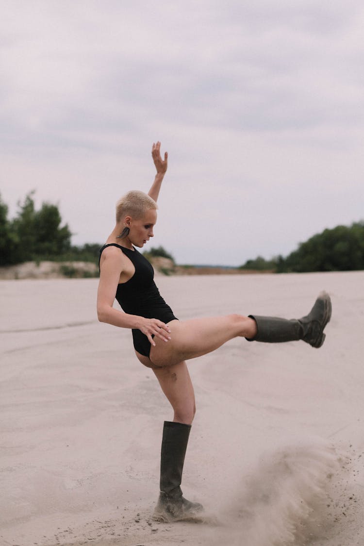 Woman In Black Swimsuit Wearing Boots On White Sand 