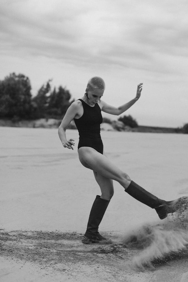 Black And White Photo Of A Woman Kicking The Sand