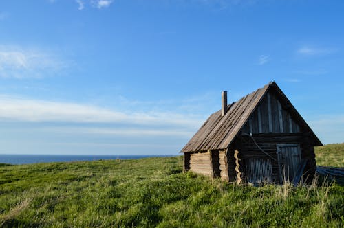 Wooden House on Grass Field under the Blue Sky