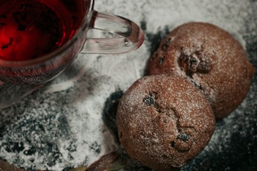 Free A close-up of delicious sugar-dusted cupcakes and a steaming cup of red tea. Stock Photo