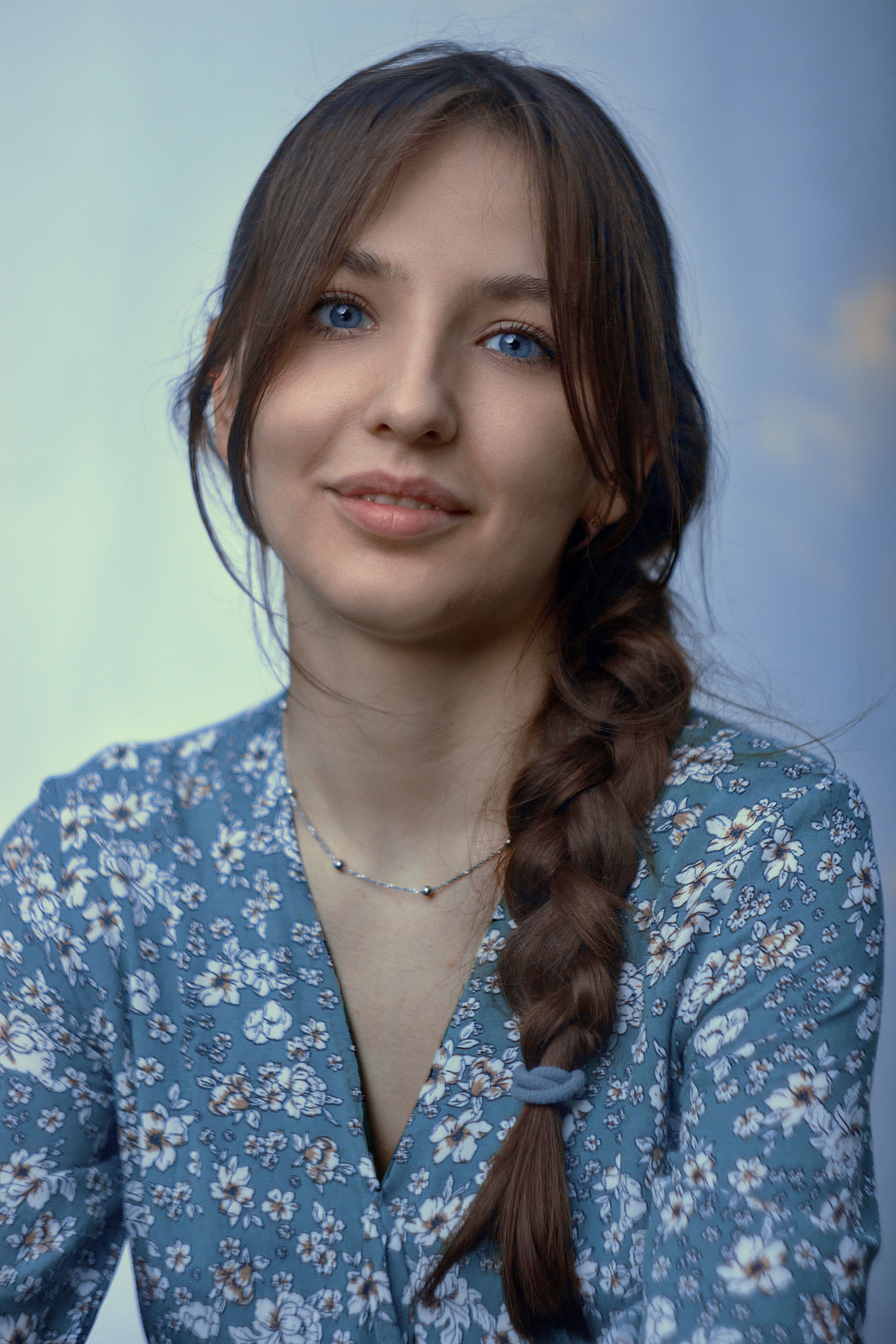 Charming close-up portrait of a woman with braided hair wearing a floral dress, showcasing natural beauty.