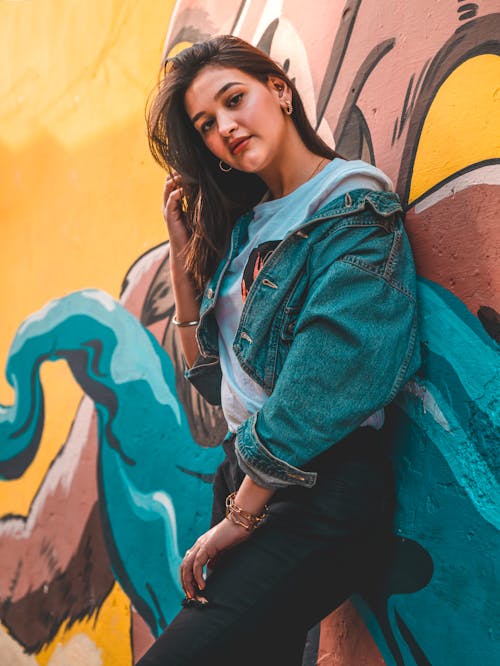 Woman in Blue Denim Jacket Leaning on Wall With Graffiti