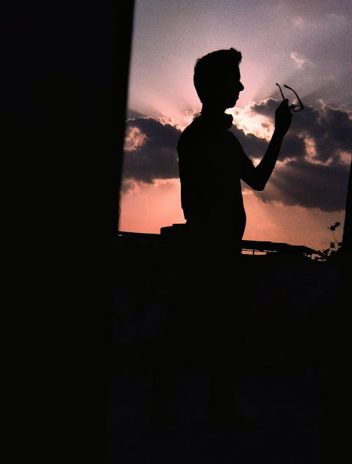 Silhouette of a Person Holding an Eyeglasses