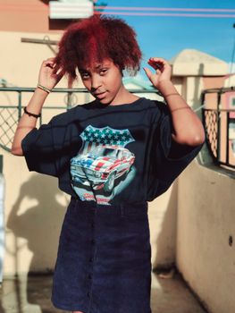 Fashionable teenager with curly red hair in Nairobi, Kenya on a sunny day.
