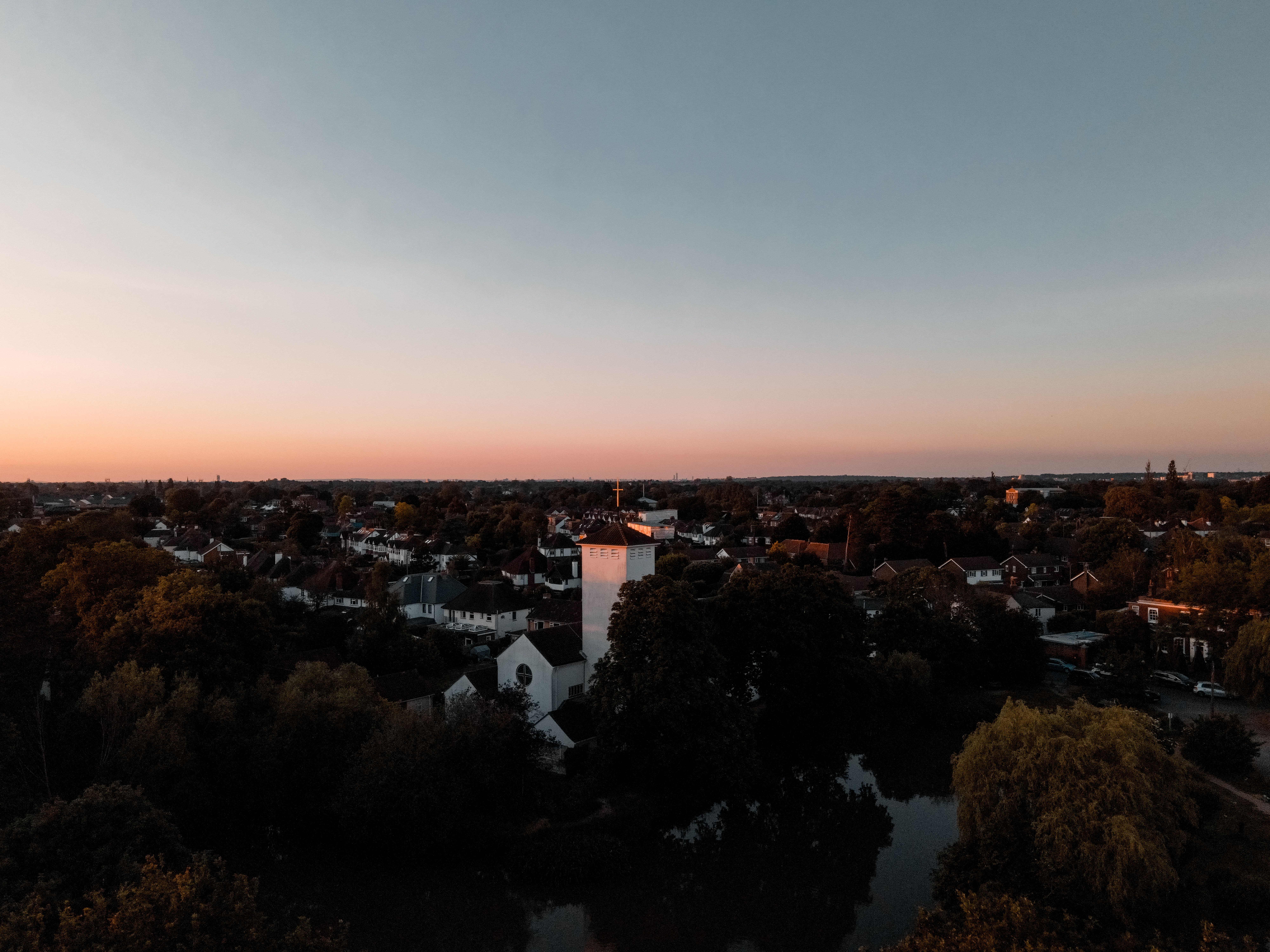 Aerial view of a Surrey neighborhood with lush greenery during sunset, showcasing tranquil beauty.