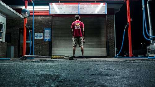 Free Man in Red Shirt and Brown Shorts Standing Near Wall Stock Photo