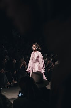 Stylish model in pink satin dress walks runway at Dubai fashion show.