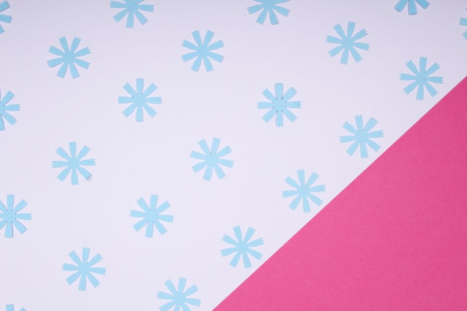 Pink and blue geometric floral pattern on seamless wallpaper design.