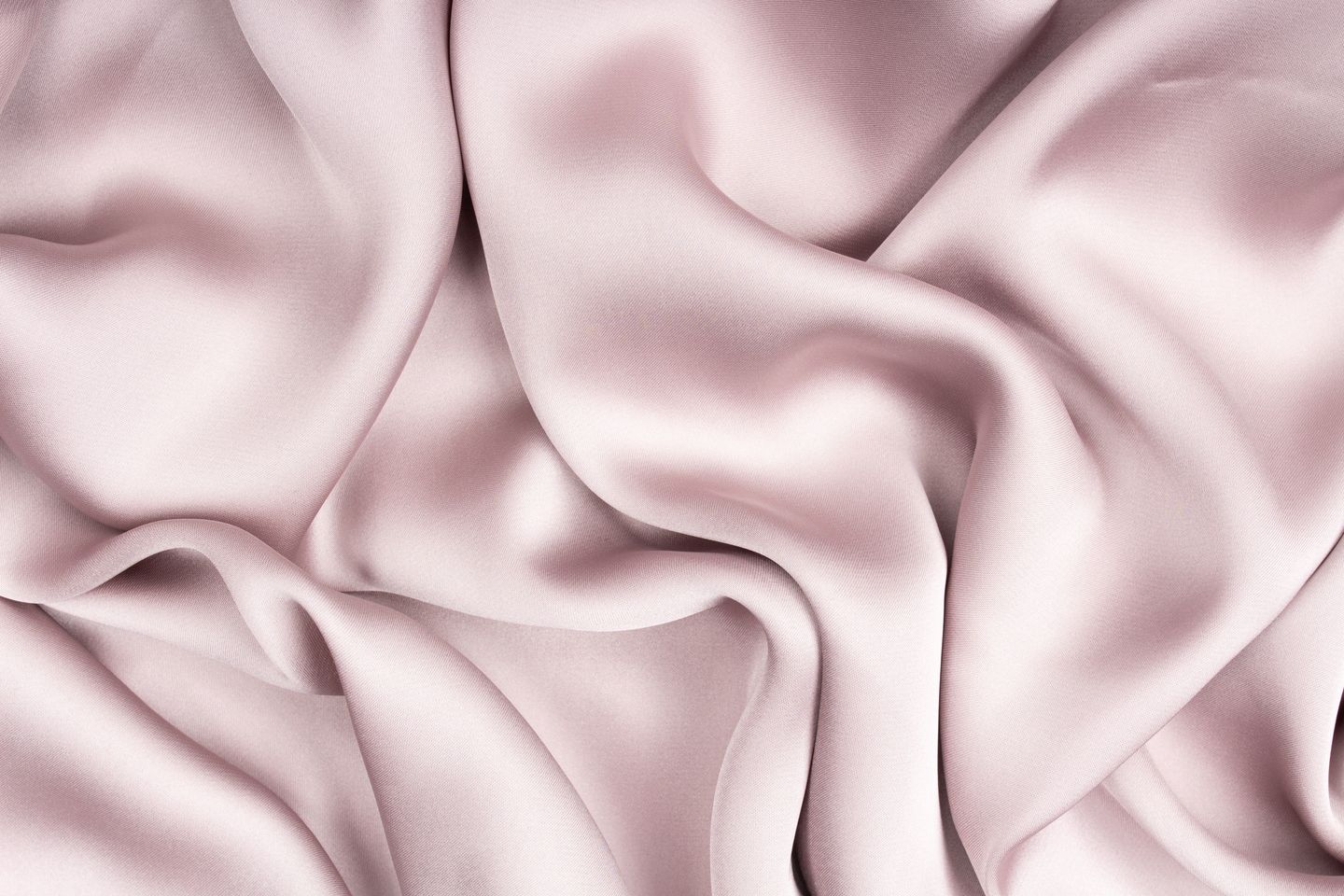 Close-up of glossy blush-lavender satin fabric in soft rippling folds