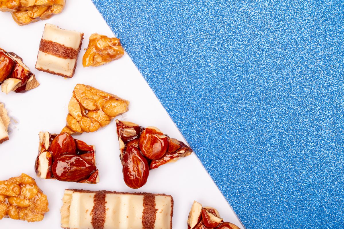 Overhead view of assorted sweets and desserts on a glittery blue background with copy space.