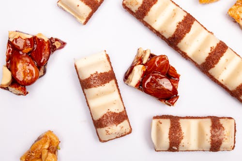 Delicious White Chocolate Bars and Glazed Nuts on White Surface