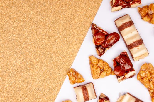 Close-up of assorted candied nuts and sweets on a white and gold background, perfect for food photography.