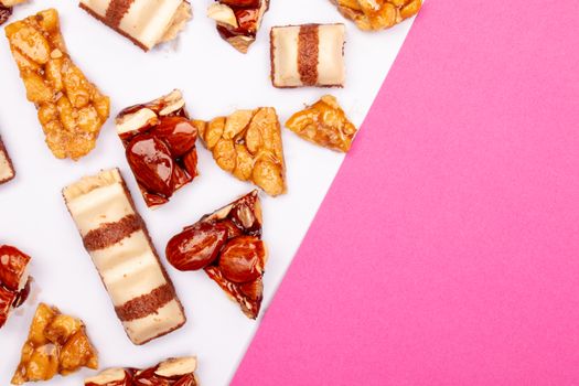 Close-up of caramel and nut treats arranged on a pink and white background.