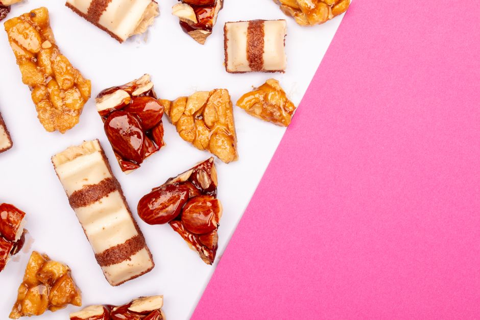 Close-up of caramel and nut treats arranged on a pink and white background.
