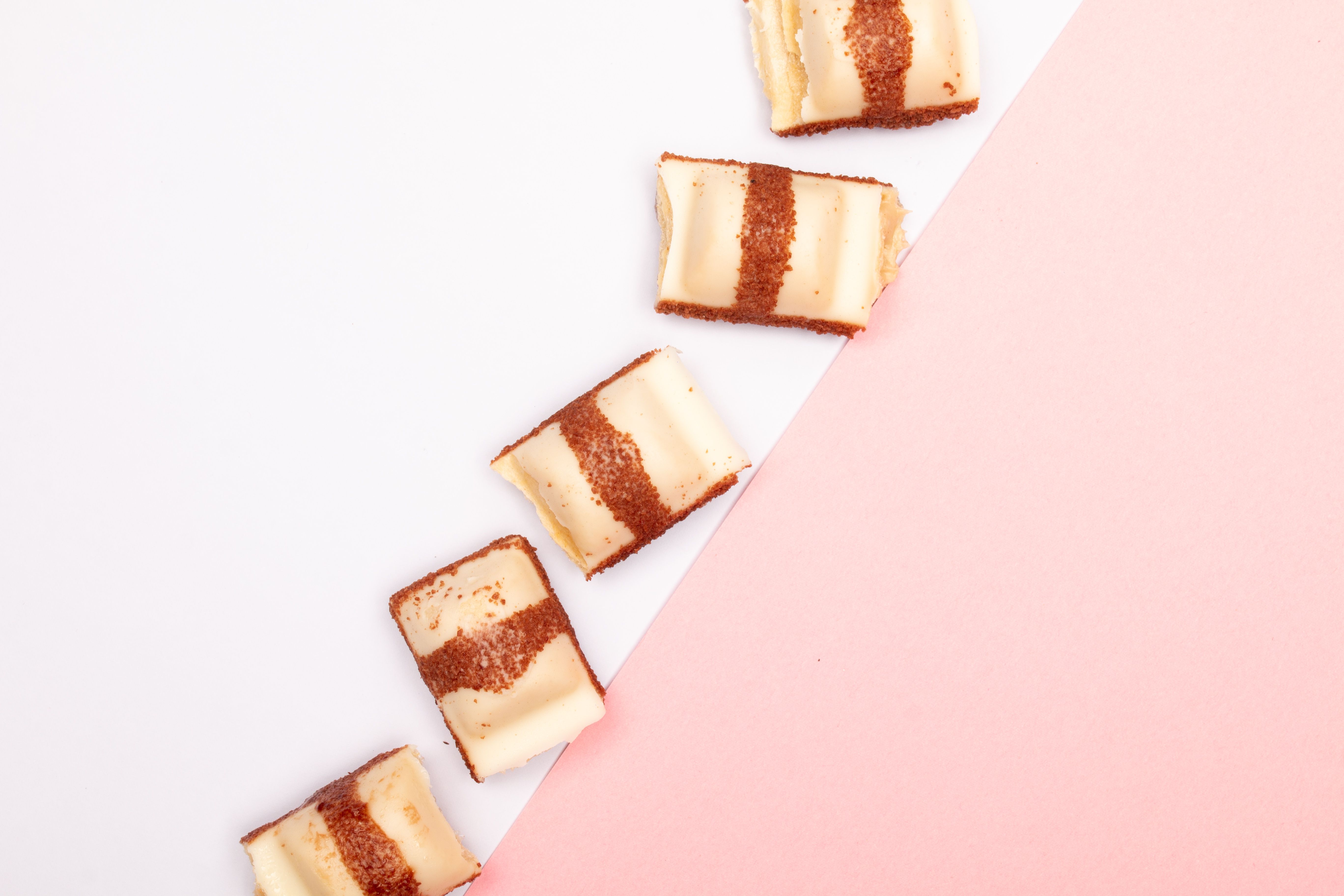 Five striped creamy cakes beautifully arranged on a diagonal pink and white background.