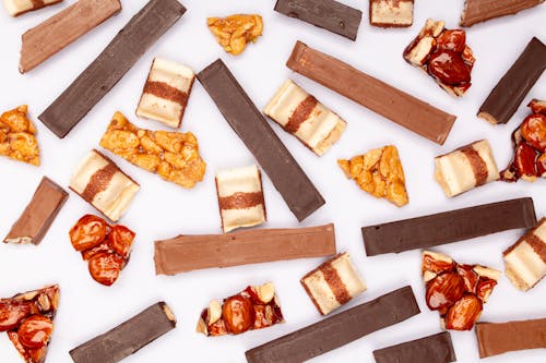 Free Kit Kat Bars and Caramel Coated Nuts on White Surface  Stock Photo
