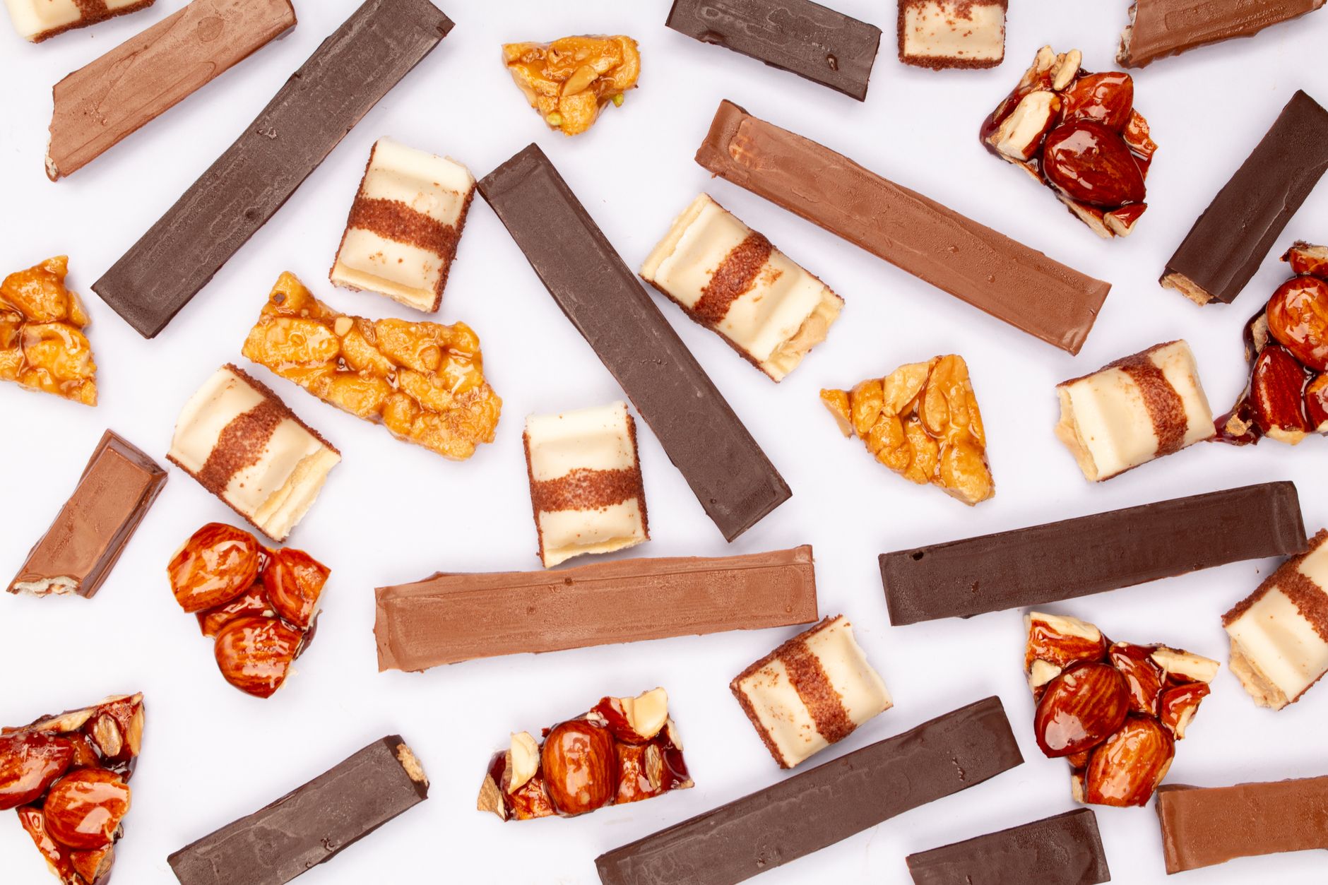 Close up of a chocolate covered almond toffee bar with nuts on a wooden board