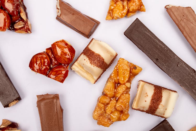 Assorted Chocolate Bars And Glazed Nuts On White Surface