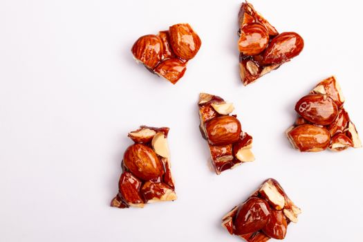 Overhead shot of almond brittle pieces placed on a white surface, showcasing delectable candy texture.