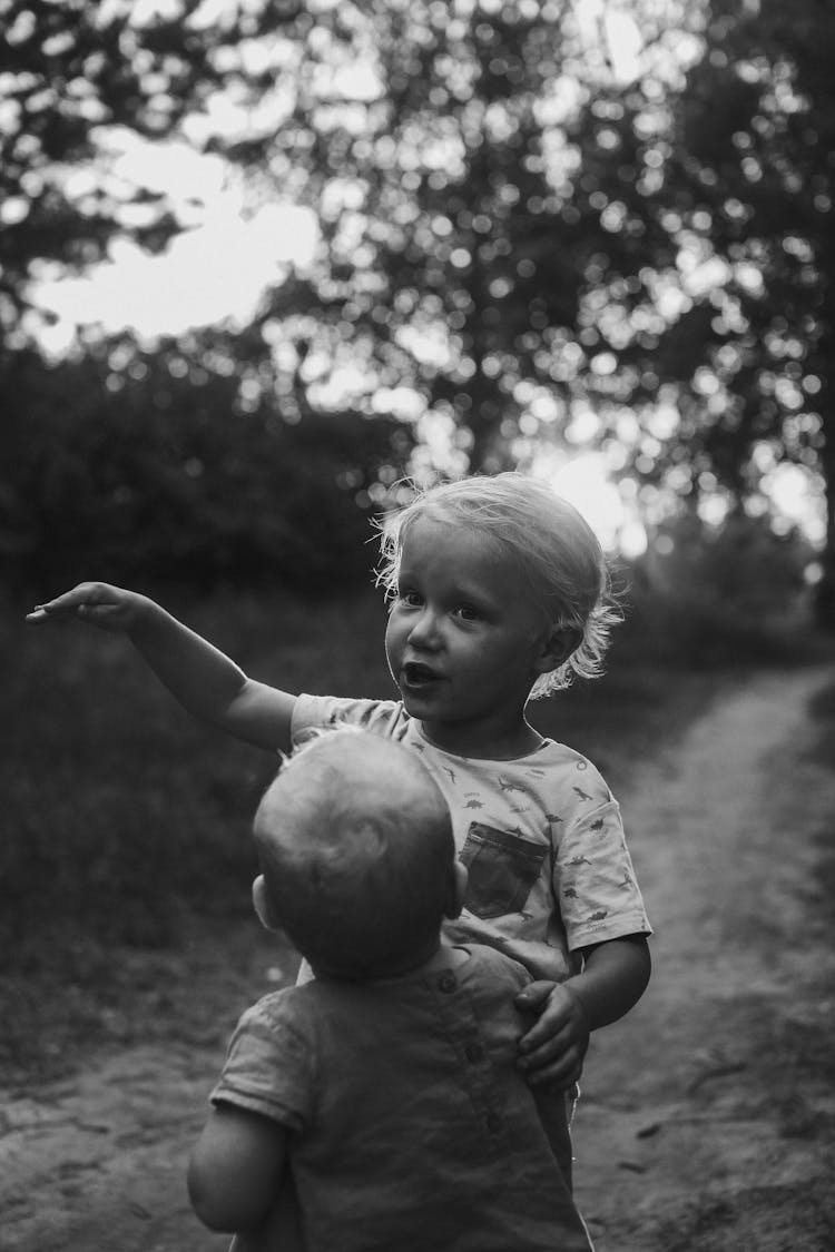 Grayscale Photo Of Two Girls Standing On A Pathway