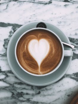 A beautifully crafted heart-shaped latte art in a ceramic cup on marble.