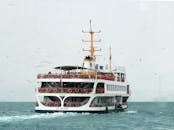 一艘白色渡轮载着乘客，在蓝天下穿越海鸥环绕的蔚蓝大海