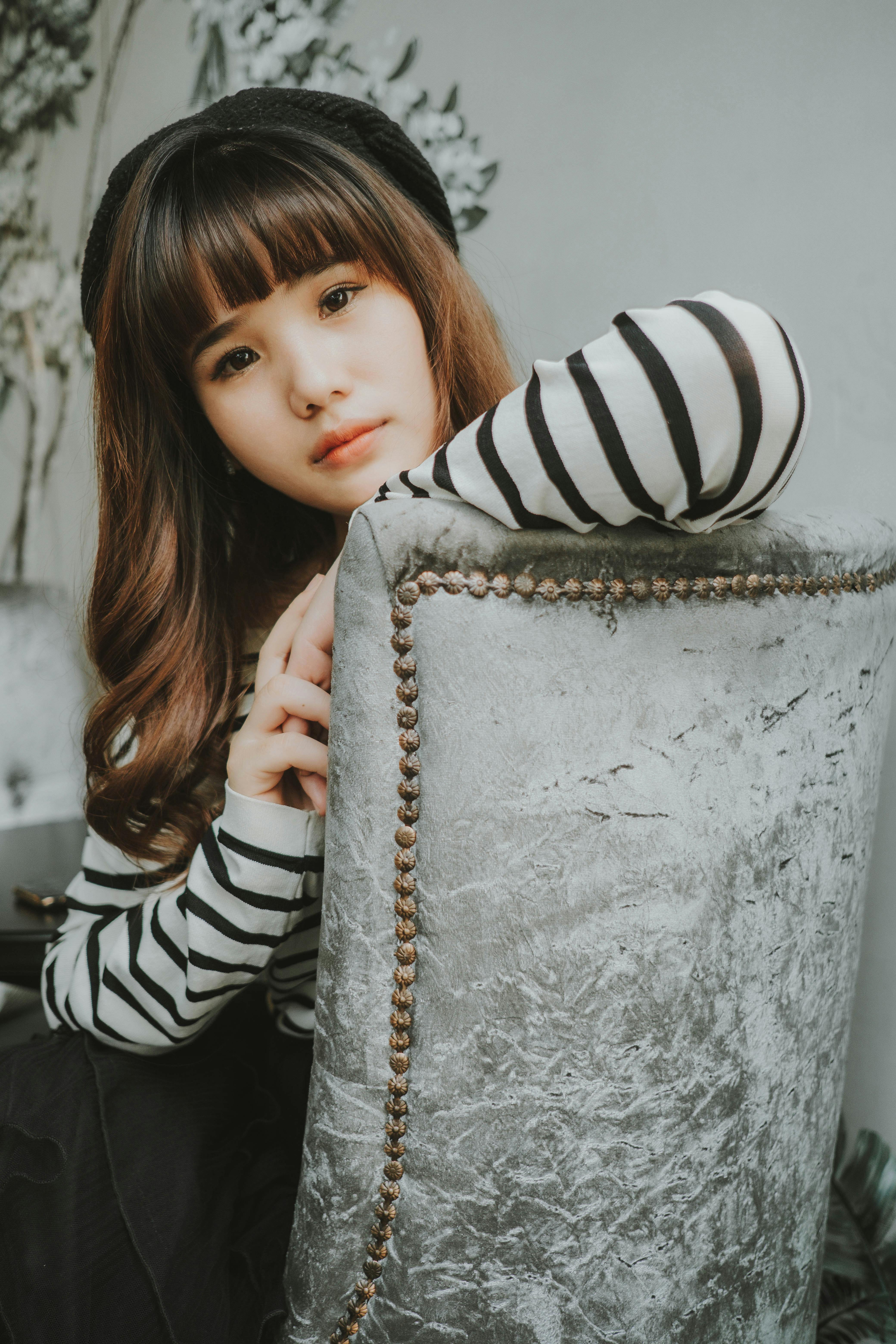 Captivating portrait of a fashionable young woman sitting indoors in striped attire.