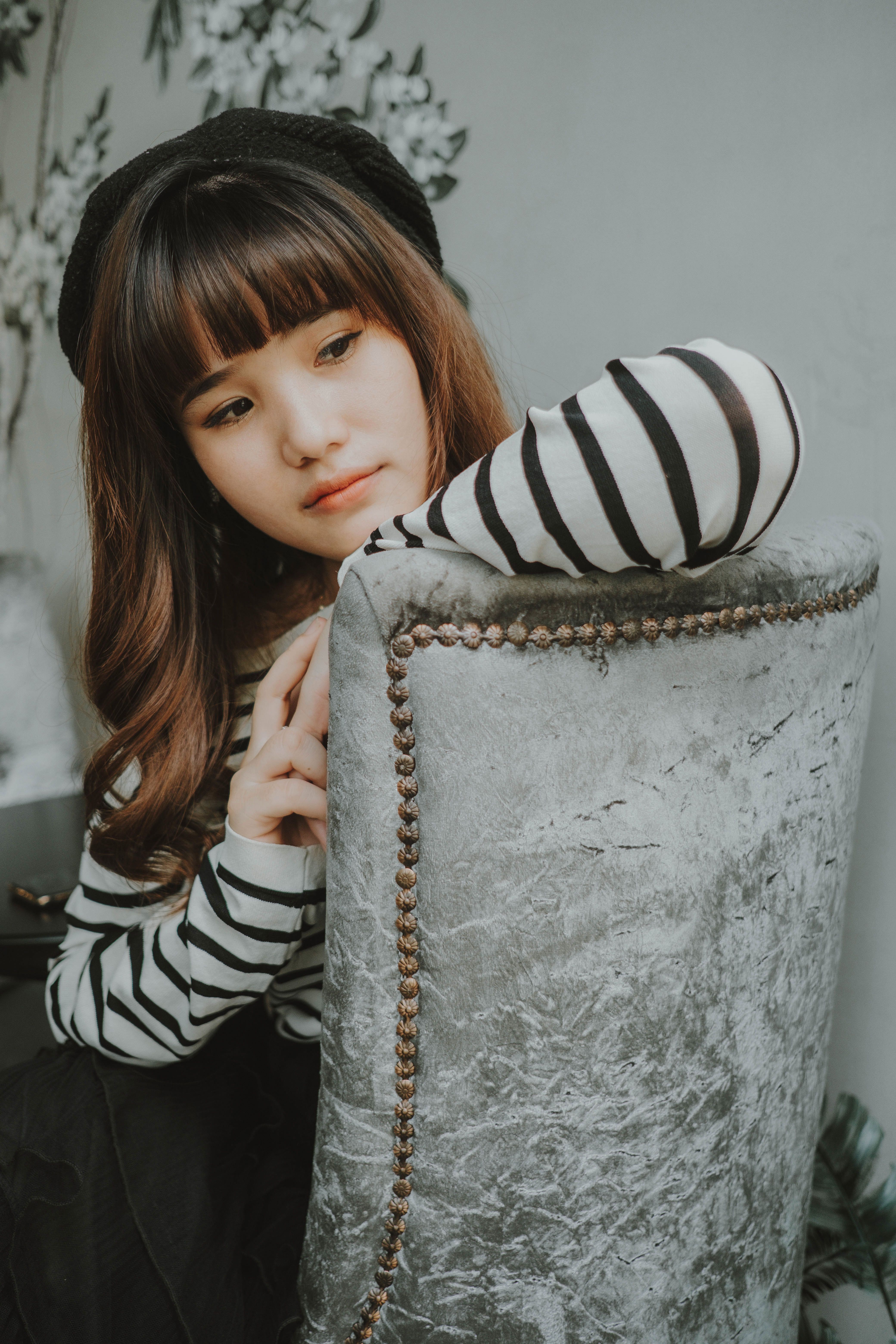Elegant portrait of an Asian woman in a striped outfit and beret, showcasing modern fashion style.
