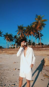 A man capturing memories on a tropical beach with a vintage camera.