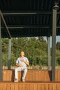 Man in White Dress Shirt Sitting on Brown Wooden Bench