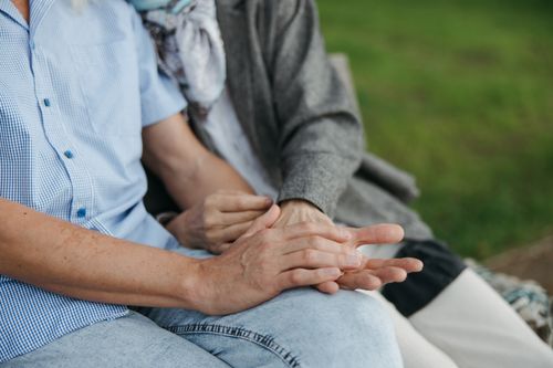 Free Close-up of elderly couple holding hands on a bench, symbolizing love and companionship. Stock Photo