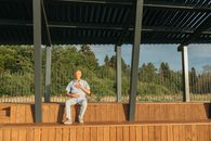 Man in White T-shirt and White Pants Standing on Brown Wooden Fence
