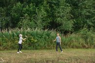Man and Woman Walking on Green Grass Field