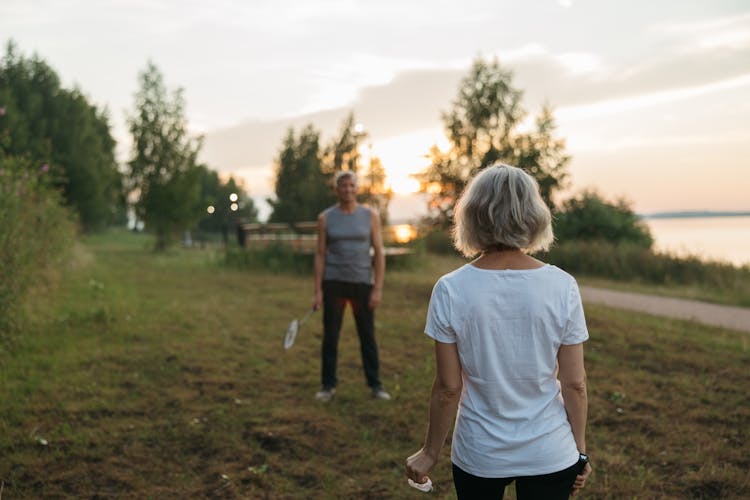 Couple Playing Badminton On Grass Field