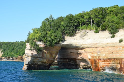 Brown Rock Formation with Green Trees near a Body of Water