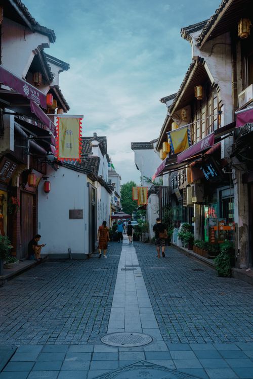 Free Charming traditional shops and lanterns line a vibrant historic street bustling with pedestrians. Stock Photo