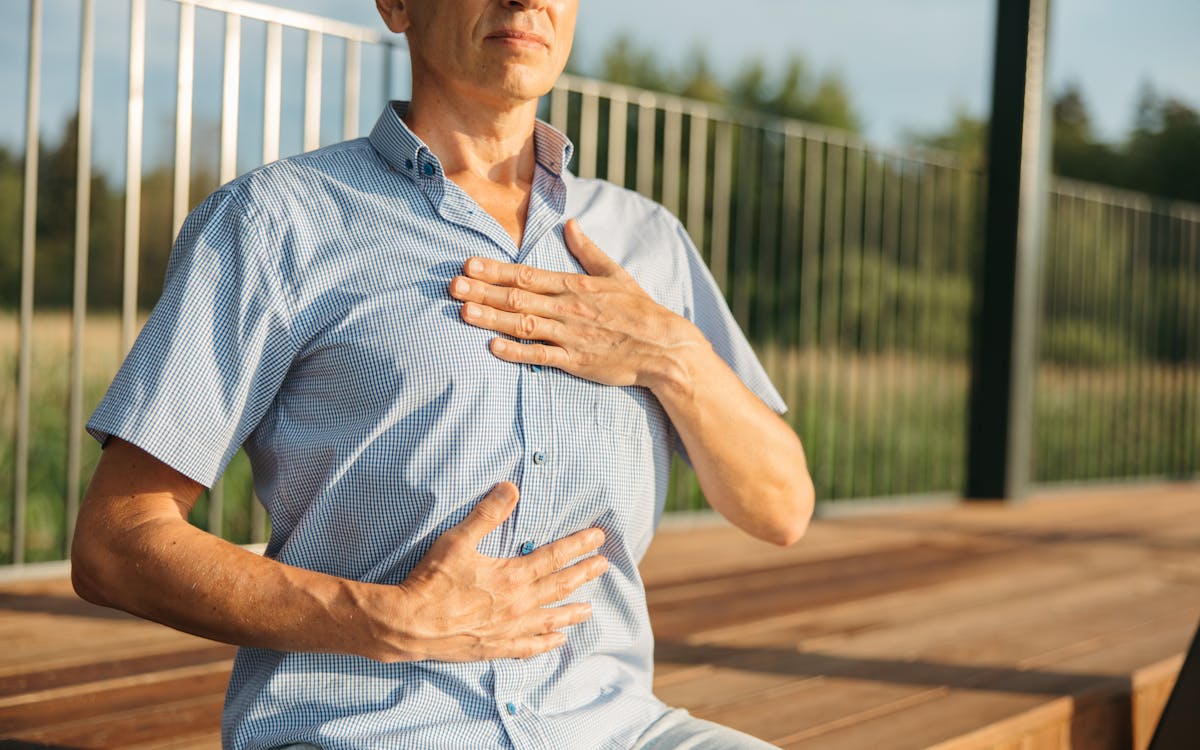 A man practicing relaxation with hands on chest and abdomen outdoors.
