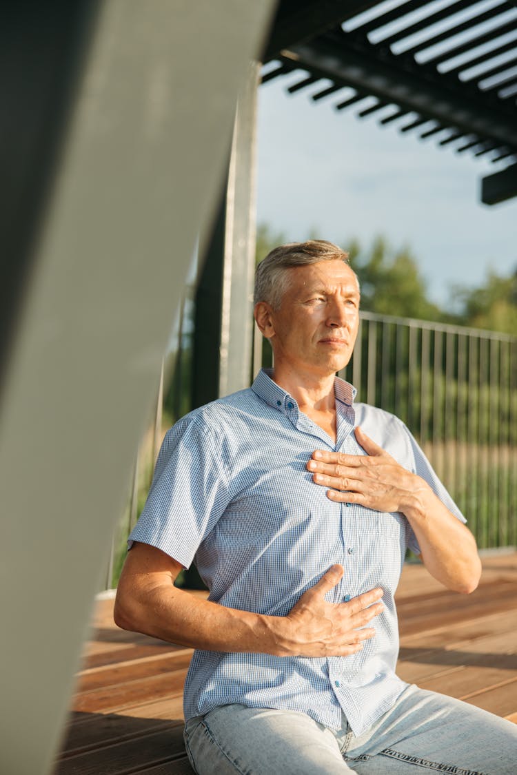 Man In Blue Polo Holding His Chest