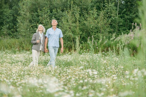 Free Man and Woman Walking on Green Grass Field Stock Photo