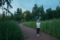 Girl in White Shirt and Black Pants Standing on Pathway Between Green Grass and Trees during