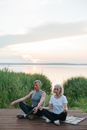 Man and Woman Sitting on Grass Field Near Body of Water